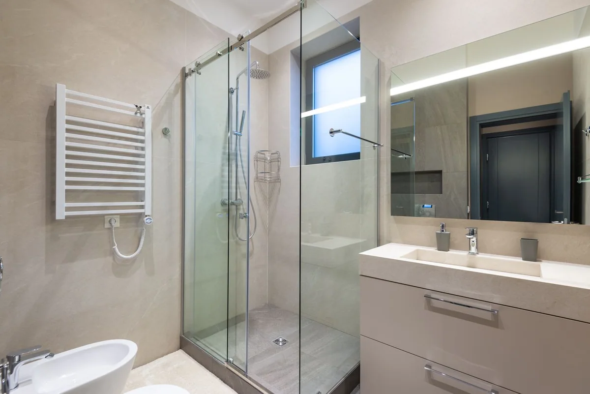 Neutral bathroom with a glass shower enclosure, mirror and vanity basin