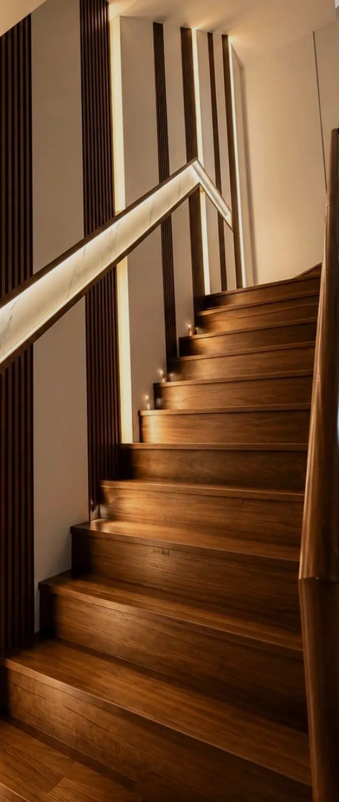 Timber staircase framed by vertical fins and integrated warm lighting